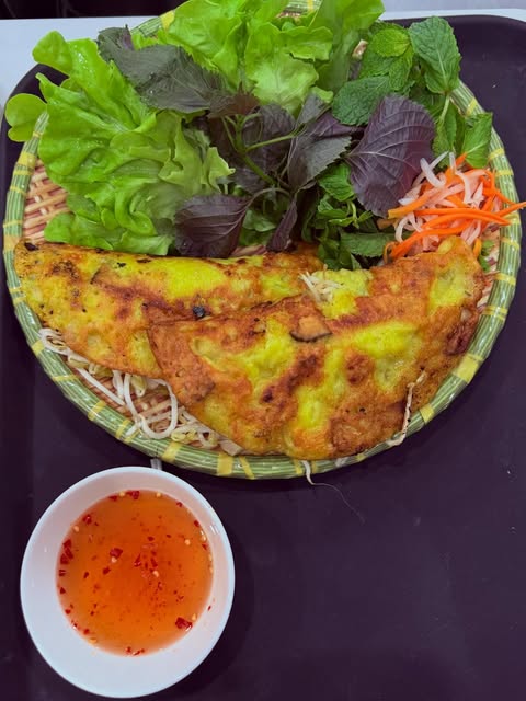 Vietnamese pork and prawn pancake with a basket of fresh herbs